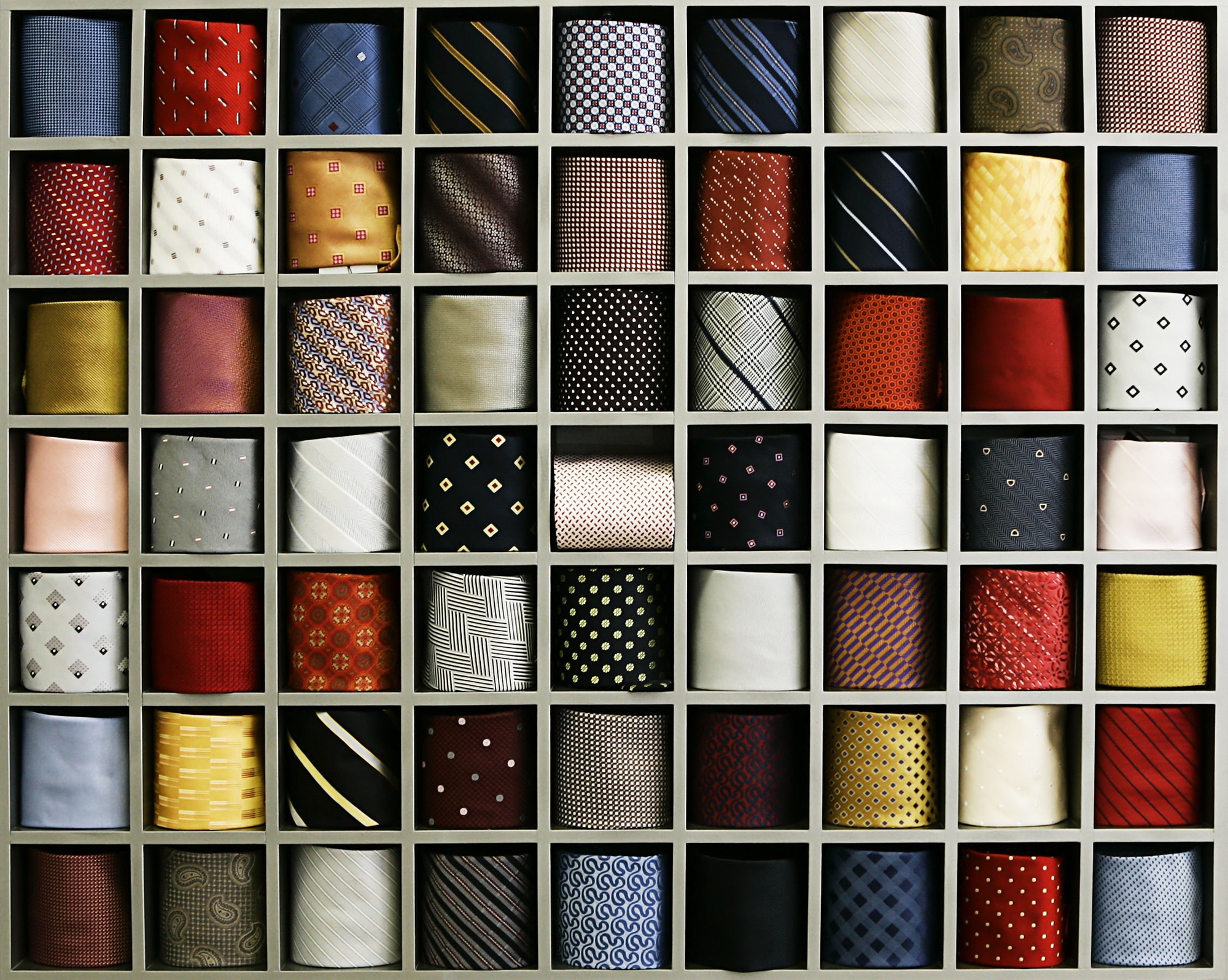 Photo of a shelf containing the collection of ties with various colors, patterns, and designs